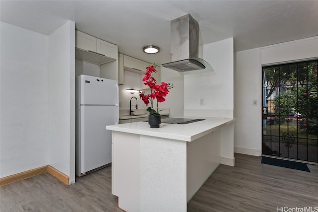 kitchen with island range hood, white cabinetry, white fridge, kitchen peninsula, and black electric cooktop