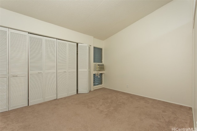 unfurnished bedroom with light colored carpet, vaulted ceiling, a textured ceiling, cooling unit, and a closet