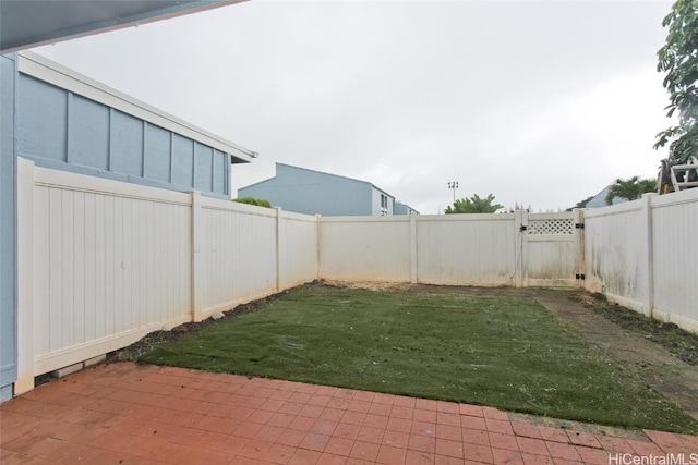 view of yard with a patio area, a fenced backyard, and a gate