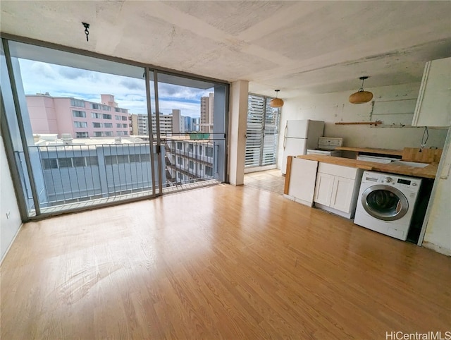 kitchen featuring a wall of windows, white fridge, light hardwood / wood-style floors, and washer / clothes dryer