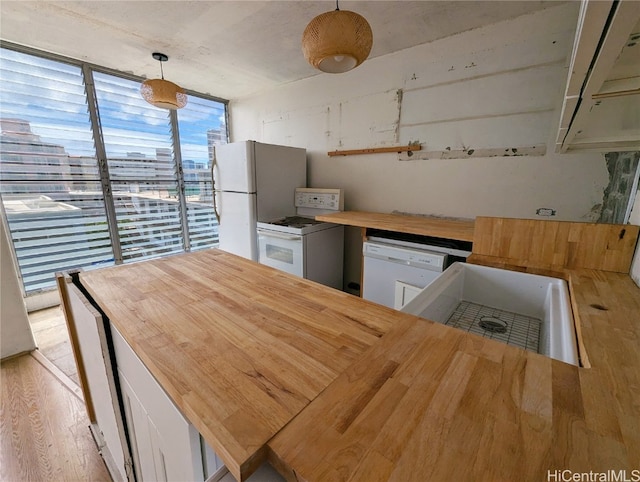 kitchen featuring pendant lighting, light hardwood / wood-style floors, sink, butcher block countertops, and white appliances