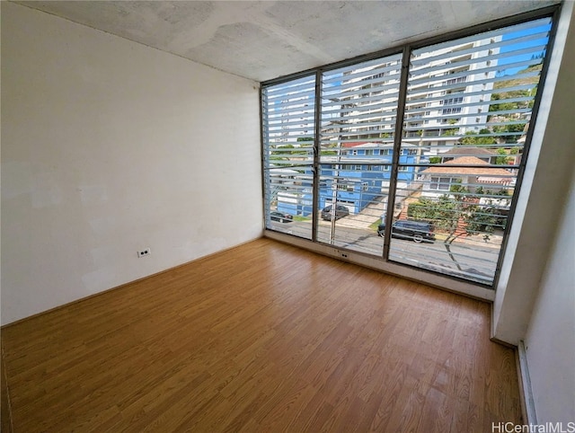 spare room with expansive windows and wood-type flooring