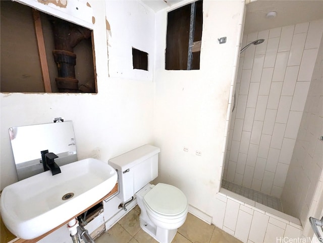 bathroom with sink, a tile shower, toilet, and tile patterned flooring