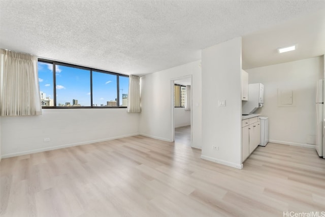 unfurnished room with light hardwood / wood-style floors and a textured ceiling