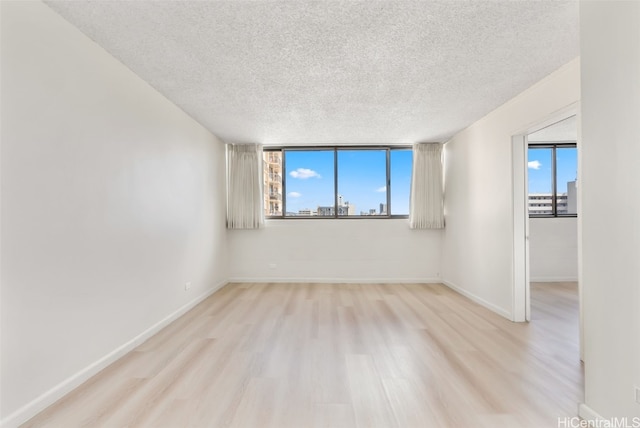 spare room featuring light hardwood / wood-style floors, a textured ceiling, and a healthy amount of sunlight