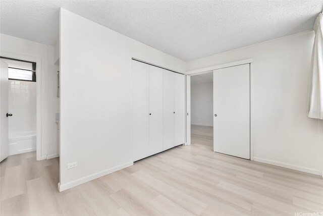 1040 Kinau St Unit 704, Honolulu, HI 96814 - unfurnished bedroom with light wood-style flooring, a textured ceiling, and baseboards