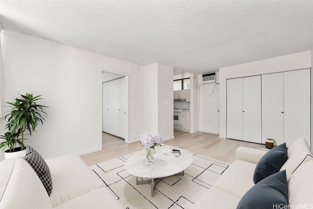 living room featuring light hardwood / wood-style floors, a textured ceiling, and a wall mounted AC