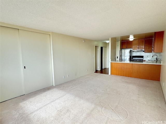 kitchen with kitchen peninsula, a textured ceiling, black gas stove, and stainless steel refrigerator