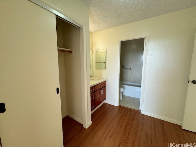 hall with sink, dark wood-type flooring, and a textured ceiling