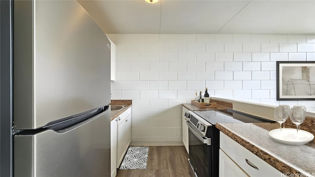 kitchen with white cabinets, dark wood-type flooring, appliances with stainless steel finishes, and tile walls