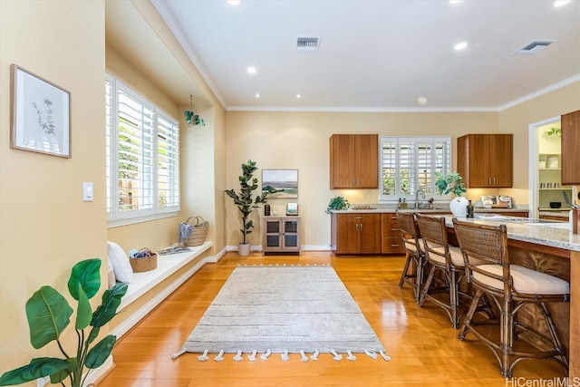 kitchen with light hardwood / wood-style floors, ornamental molding, and plenty of natural light