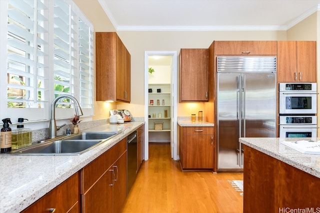 kitchen featuring stainless steel appliances, ornamental molding, sink, and light wood-type flooring