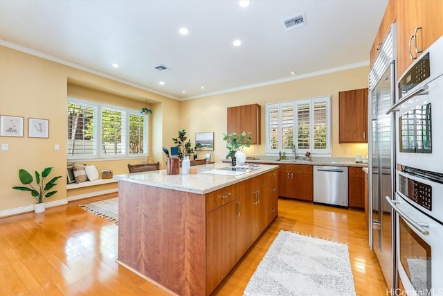 kitchen featuring a kitchen island, appliances with stainless steel finishes, light hardwood / wood-style flooring, and a healthy amount of sunlight