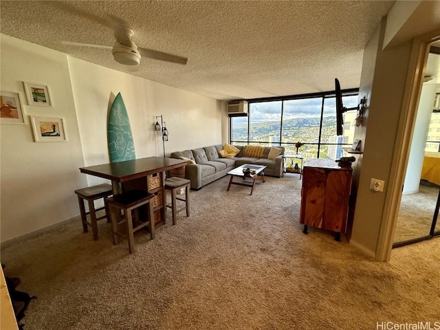 carpeted living room with ceiling fan, a textured ceiling, a wall of windows, and a mountain view