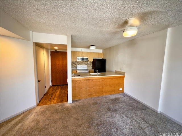 kitchen with tasteful backsplash, white range with electric cooktop, black fridge, kitchen peninsula, and dark carpet