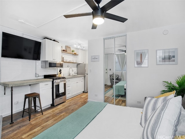 kitchen with appliances with stainless steel finishes, ceiling fan, white cabinetry, and light hardwood / wood-style floors