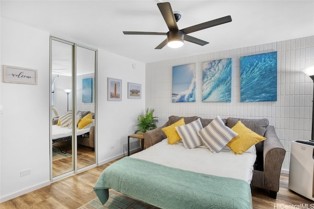 bedroom with ceiling fan, tile walls, and hardwood / wood-style floors