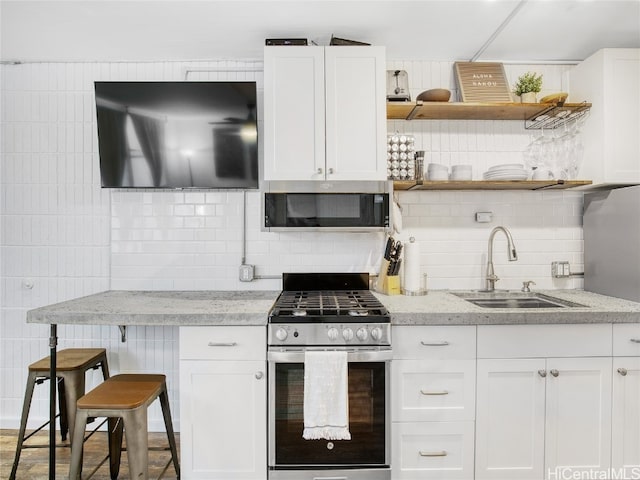 kitchen with appliances with stainless steel finishes, white cabinets, tasteful backsplash, and sink