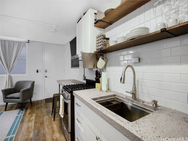 kitchen featuring sink, dark hardwood / wood-style flooring, stainless steel gas range oven, white cabinets, and tasteful backsplash