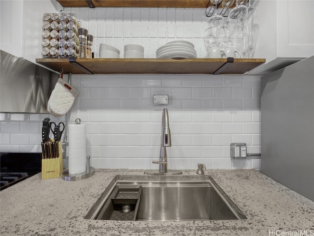 kitchen featuring white cabinetry, light stone counters, decorative backsplash, and sink