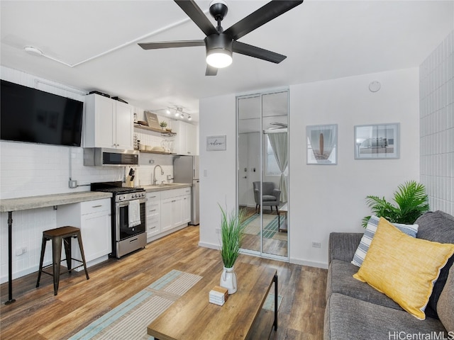 living room featuring light hardwood / wood-style floors, sink, and ceiling fan