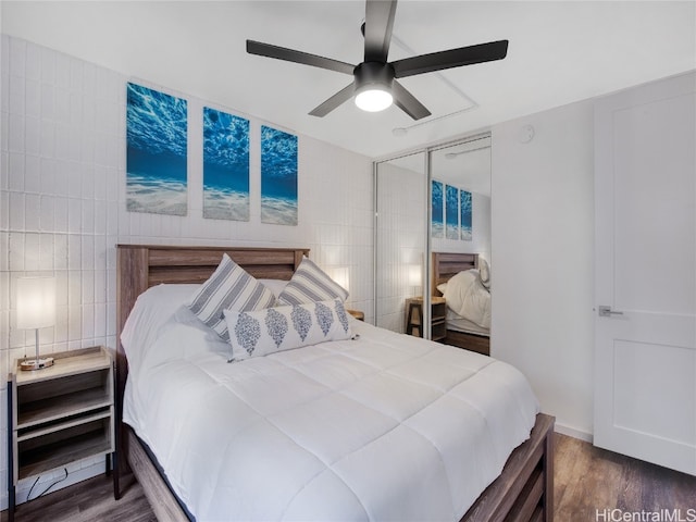 bedroom featuring a closet, ceiling fan, tile walls, and dark hardwood / wood-style flooring