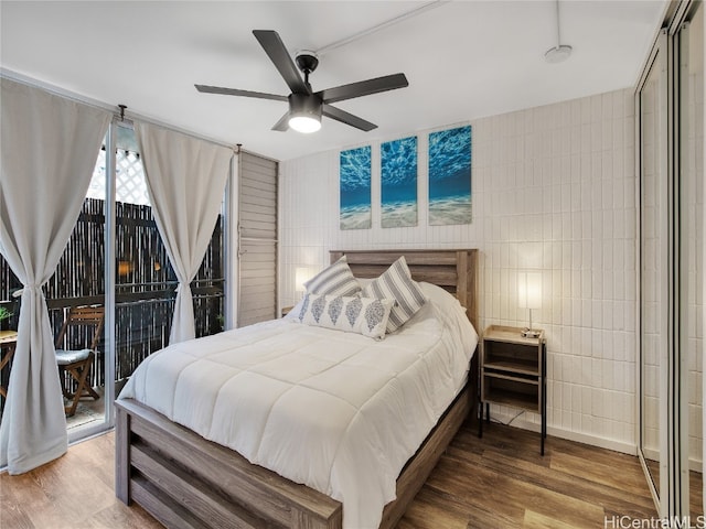 bedroom featuring tile walls, hardwood / wood-style flooring, access to outside, and ceiling fan