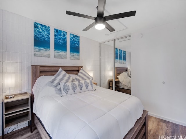 bedroom featuring tile walls, hardwood / wood-style flooring, a closet, and ceiling fan