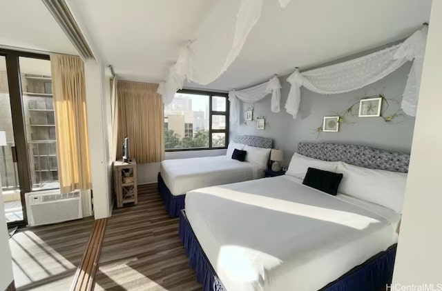 bedroom with breakfast area, a wall mounted air conditioner, and dark hardwood / wood-style floors