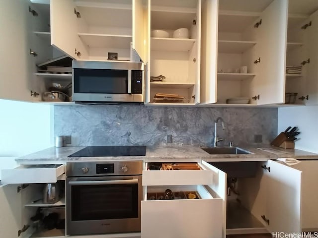 kitchen with a sink, appliances with stainless steel finishes, decorative backsplash, light stone countertops, and open shelves