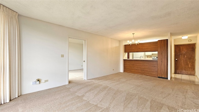 unfurnished living room featuring a textured ceiling, a notable chandelier, and light colored carpet