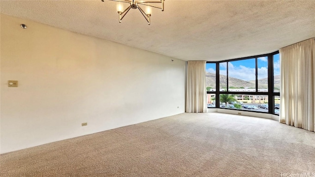 spare room with carpet floors, expansive windows, a mountain view, and a textured ceiling