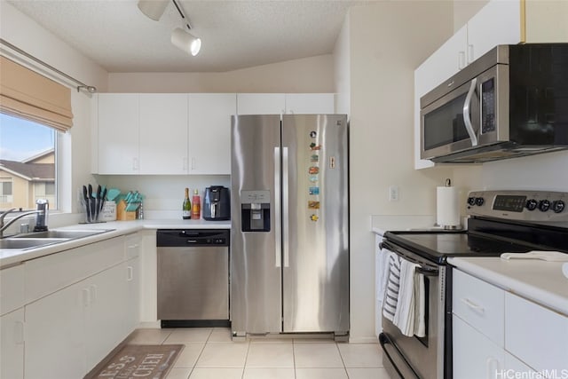 kitchen featuring white cabinetry, appliances with stainless steel finishes, a textured ceiling, light tile patterned floors, and lofted ceiling