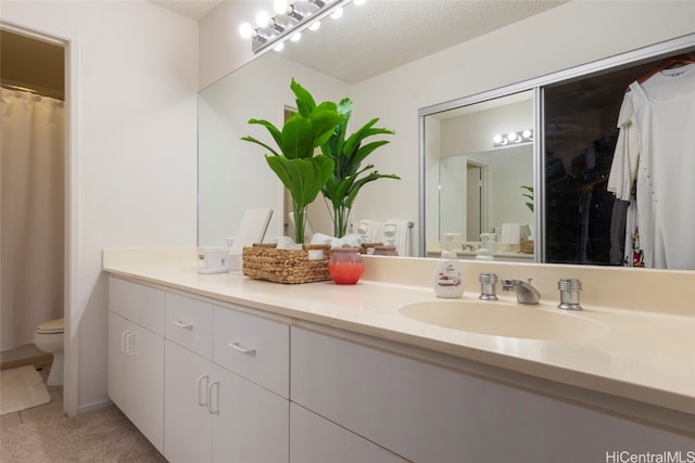 bathroom featuring vanity, a textured ceiling, and toilet