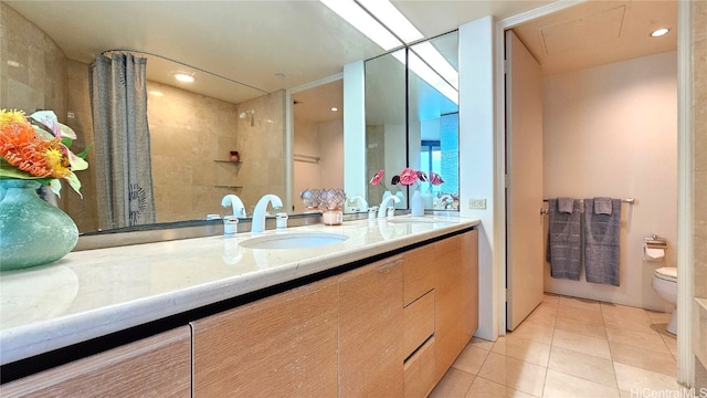 bathroom with tile patterned floors, vanity, a tile shower, and toilet