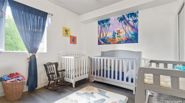 bedroom with a nursery area and dark hardwood / wood-style floors