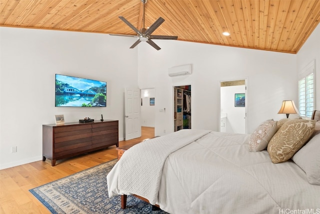 bedroom with wooden ceiling, a walk in closet, hardwood / wood-style flooring, ceiling fan, and a wall unit AC