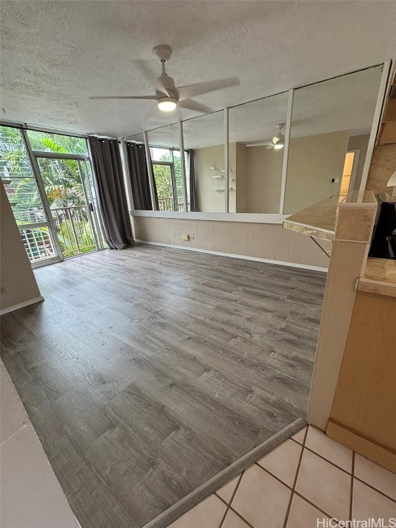 interior space with ceiling fan, wood-type flooring, a textured ceiling, and floor to ceiling windows