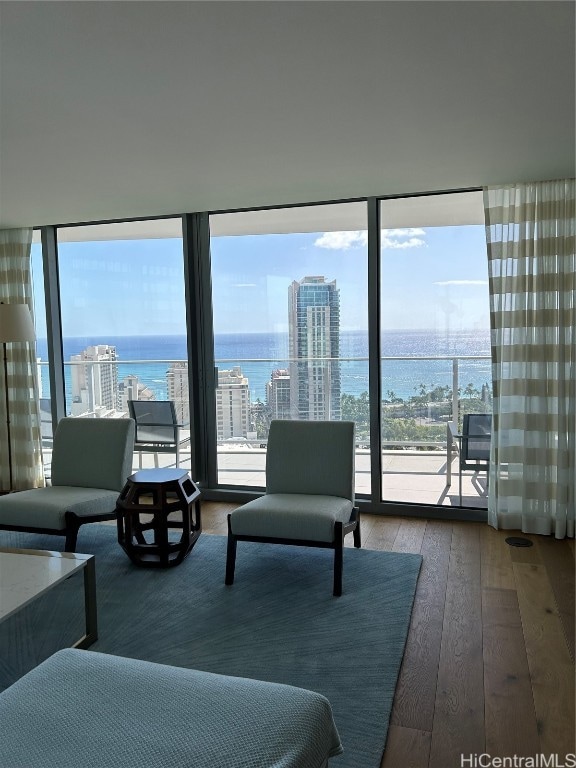 living room with a wall of windows, a healthy amount of sunlight, wood-type flooring, and a water view