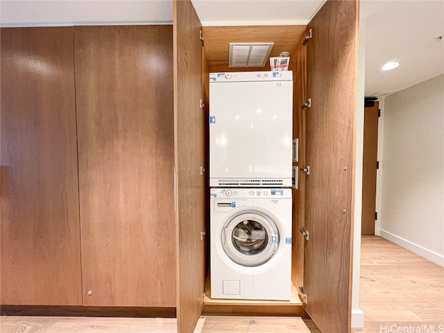 laundry room with stacked washer and dryer and light wood-type flooring