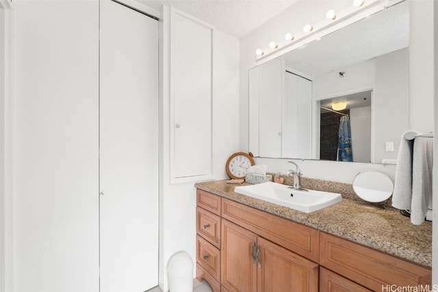 bathroom with vanity, a textured ceiling, and walk in shower