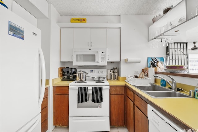 kitchen featuring sink, light tile patterned flooring, white cabinetry, a textured ceiling, and white appliances