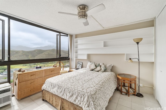 bedroom with multiple windows, a mountain view, a textured ceiling, and ceiling fan