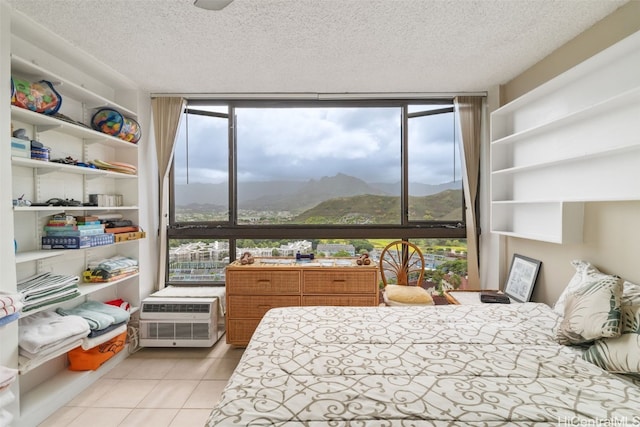 bedroom with multiple windows, a mountain view, and a textured ceiling