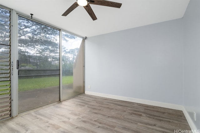 interior space featuring ceiling fan, light hardwood / wood-style flooring, and a wall of windows