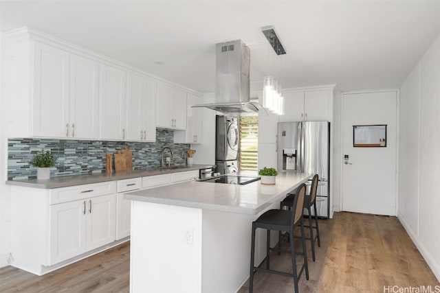 kitchen with light hardwood / wood-style floors, white cabinetry, appliances with stainless steel finishes, decorative light fixtures, and island exhaust hood