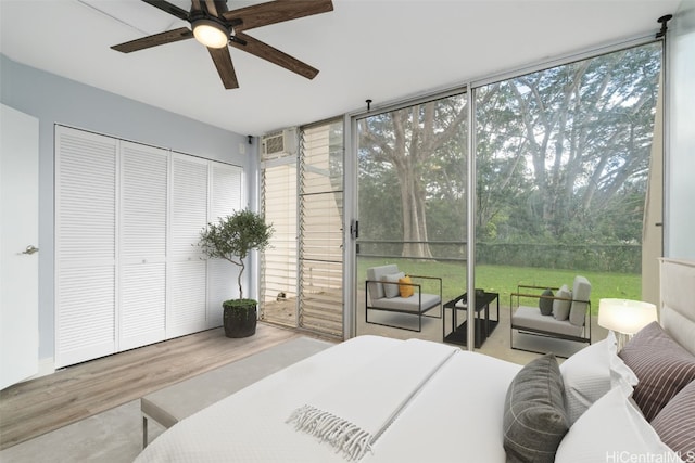 bedroom featuring an AC wall unit, wood-type flooring, ceiling fan, and access to exterior