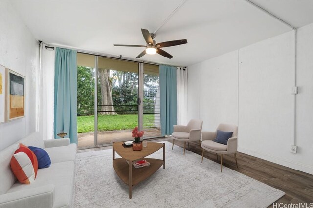 living room featuring hardwood / wood-style floors, ceiling fan, and a wall of windows