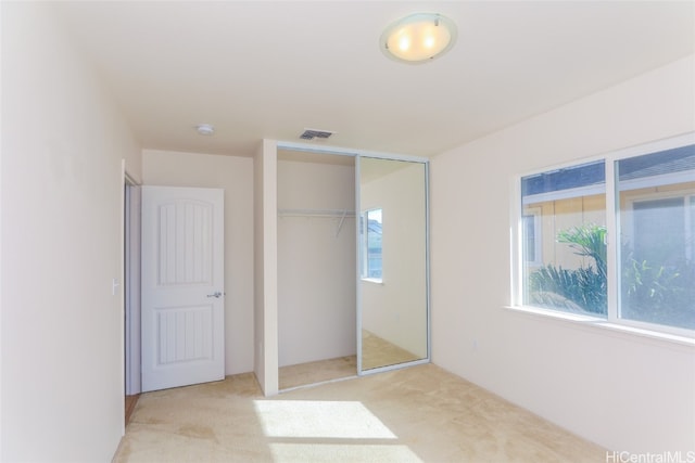 unfurnished bedroom with a closet and light colored carpet