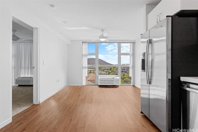 kitchen featuring ceiling fan, stainless steel appliances, light hardwood / wood-style floors, a textured ceiling, and white cabinets